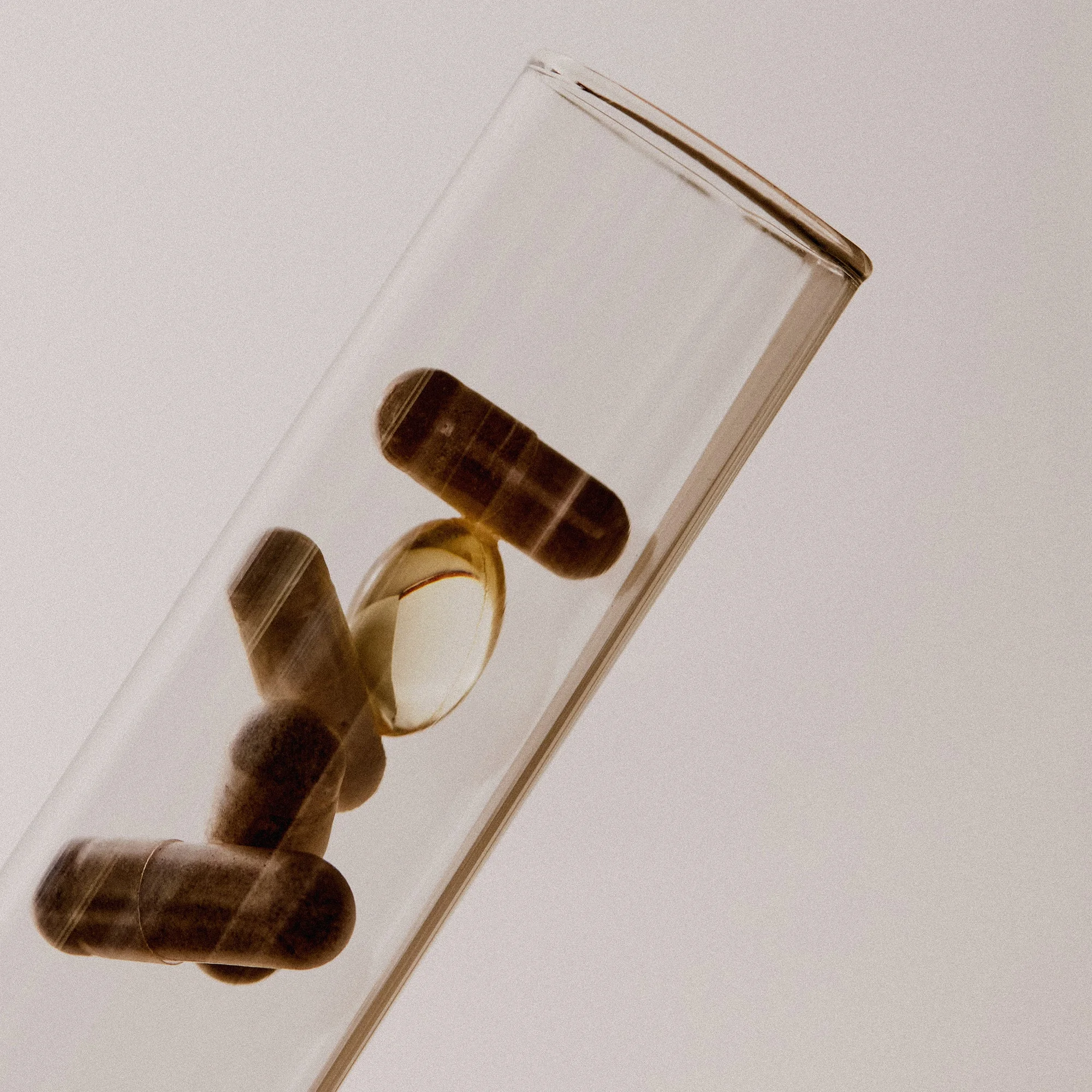 Capsules inside a glass tube on a soft beige background