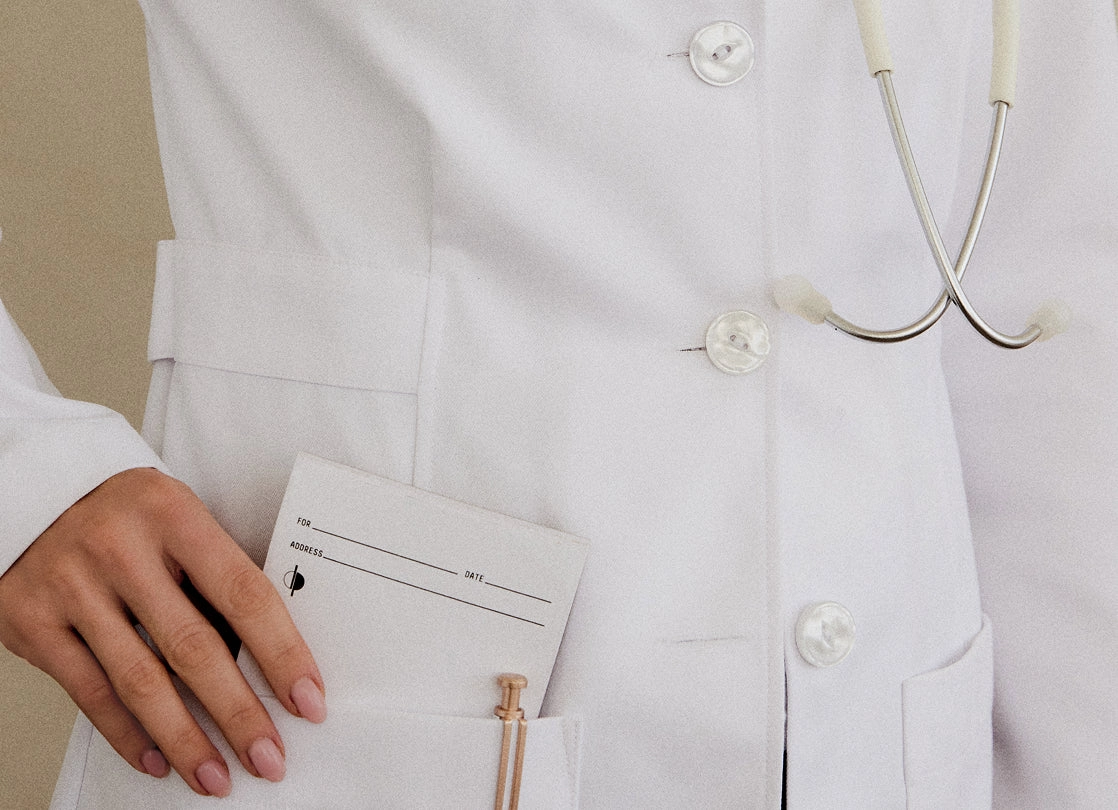 Close-up of a doctor in a white coat with a stethoscope and a card in the pocket